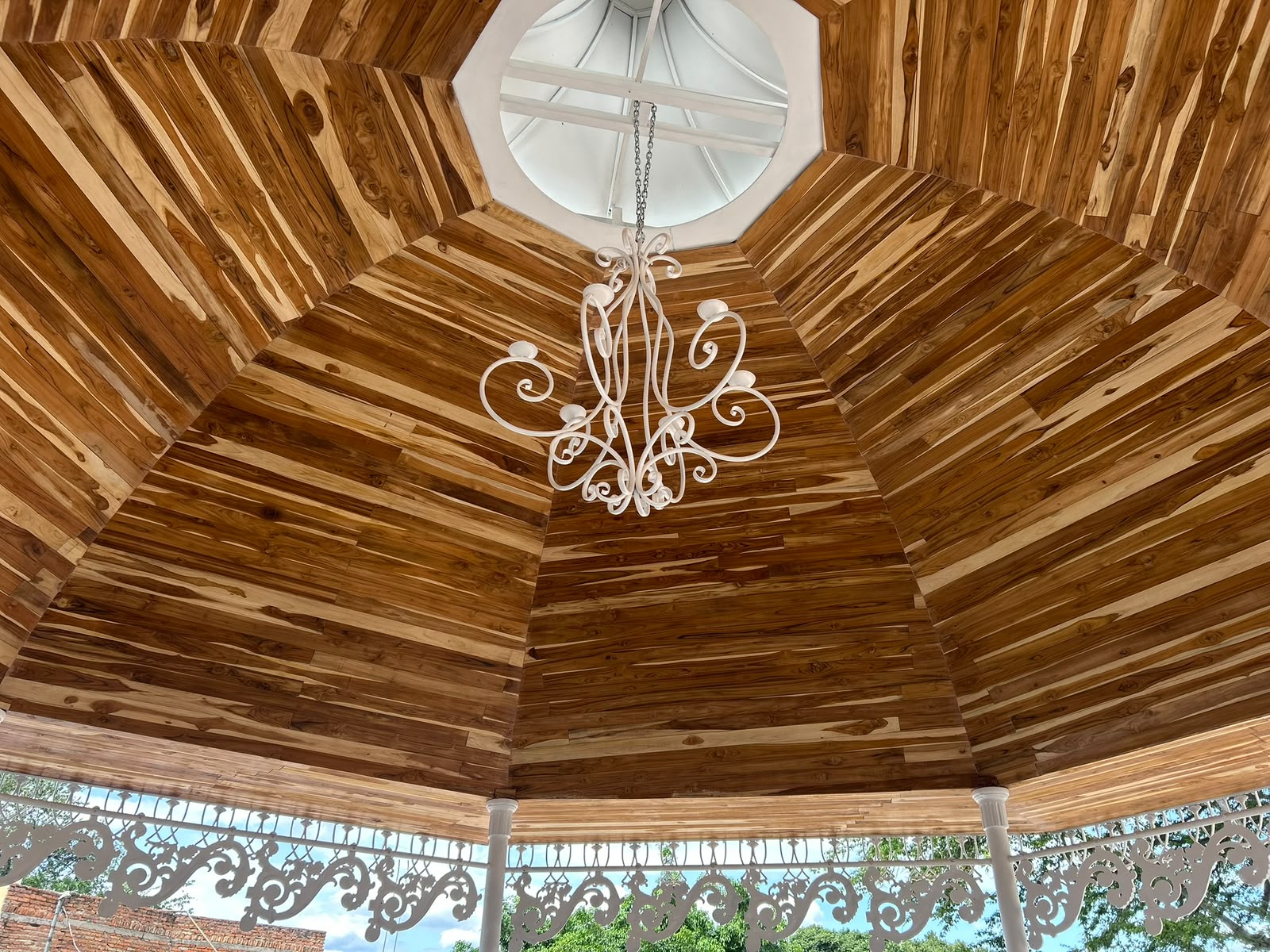 Cúpula interior de madera con lámpara de herrería del quiosco terminado